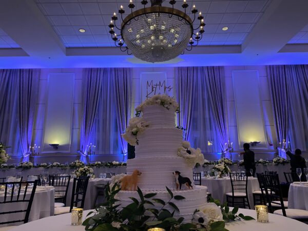 Elegant wedding reception in The Inn at St. John’s Grand Ballroom featuring a 4-tiered cake, blue uplighting, and The Inn at St. John's wedding