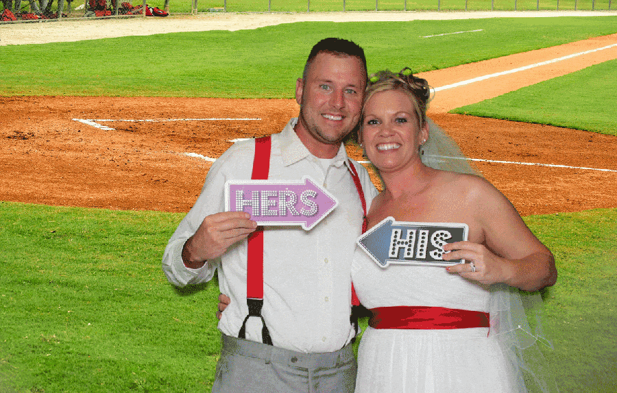 Bride and groom creating a fun animated GIF using a green screen photo booth with a baseball field backdrop at a Metro Detroit event.