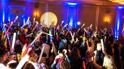 Students enjoying a high-energy Michigan school dance with LED foam light sticks, professional DJ entertainment, interactive lighting, and a packed dance floor.